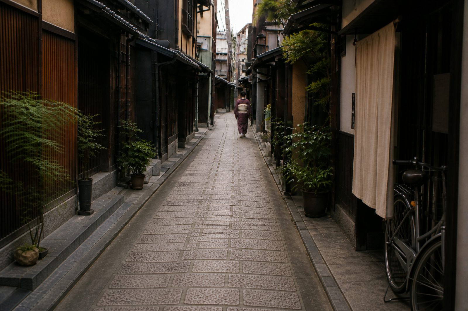 Further down the lane, the woman walks on past a small shopfront with a plain curtain and an old bicycle leaning against the wall.